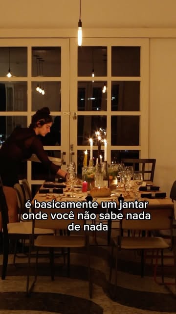 Anfitriã prepara mesa à luz de velas com taças e flores para o Jantar Misterioso.