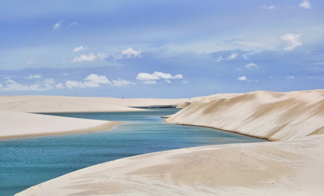Blue rainwater lagoon between white sand dunes in Lençóis Maranhenses