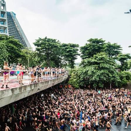 Crowd celebrating street Carnival beneath a pedestrian walkway in Rio de Janeiro